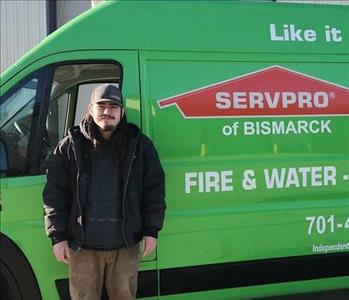 Guy with long black hair and hat standing in front of green van